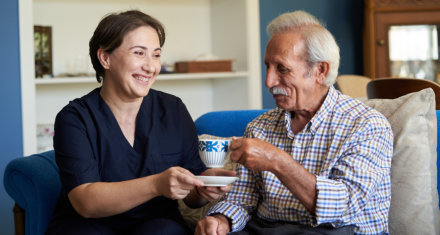 Caregiver giving coffee to her patient