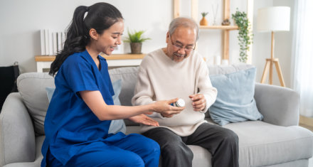 female caregiver giving medicine to elderly man