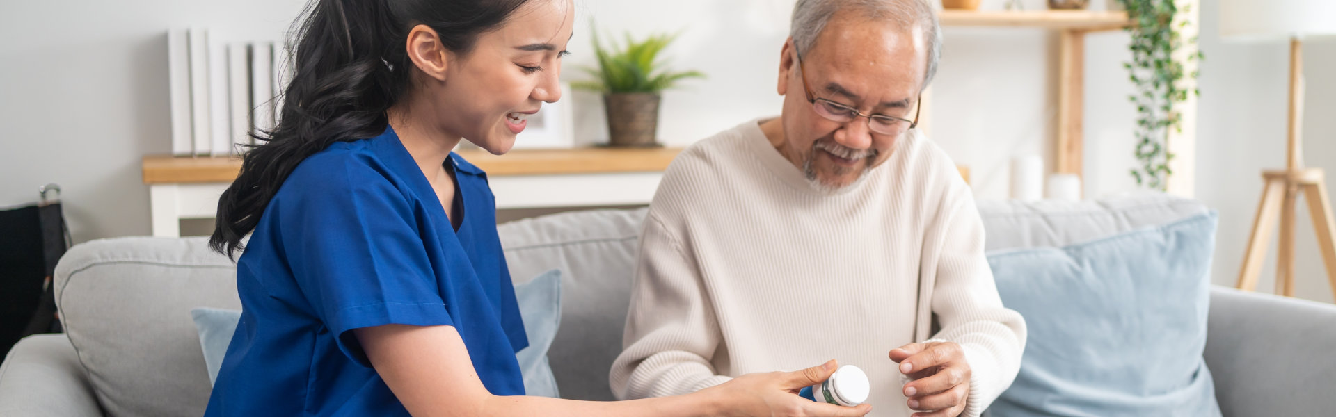 female caregiver giving medicine to elderly man