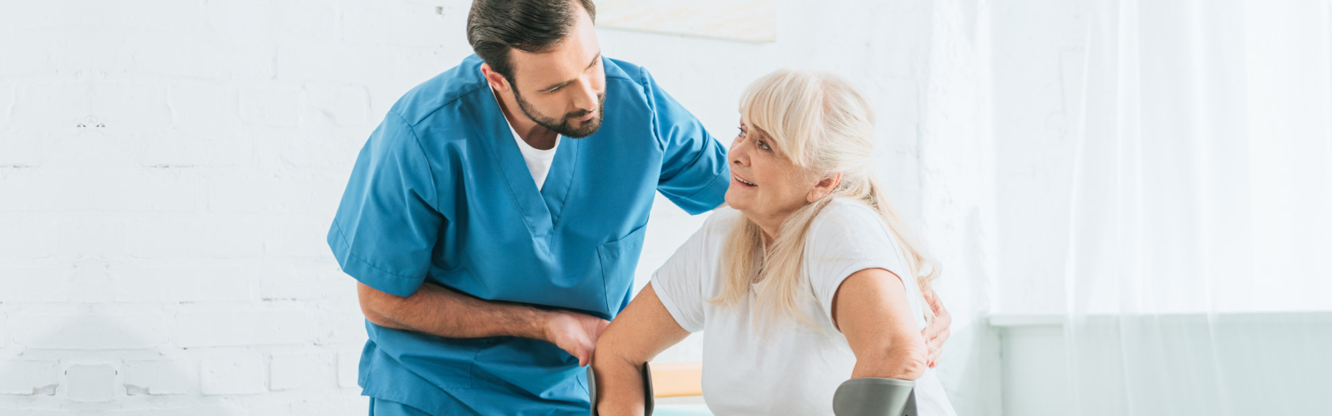 male caregiver assisting an elderly woman to stand