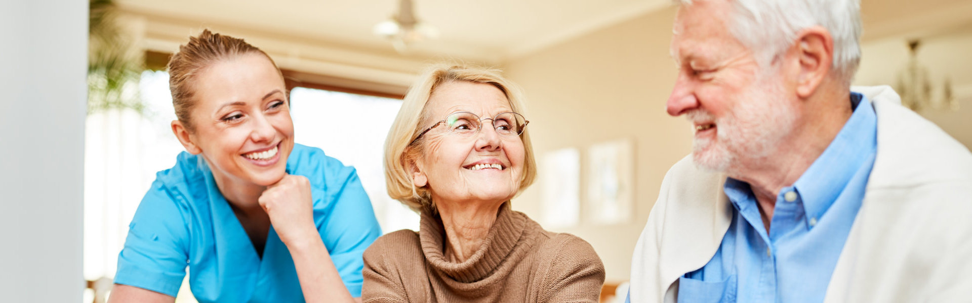 female caregiver smiling at elderly couple