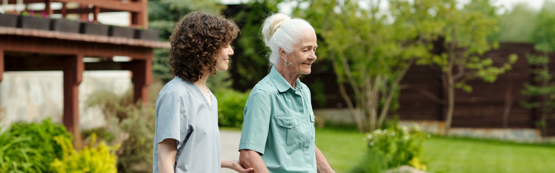 female caregiver with elderly woman walking outside